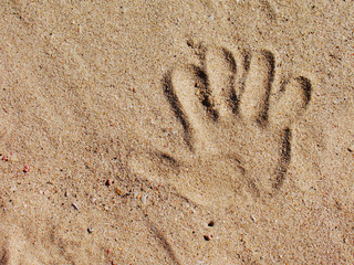Small kids handprint in the sand on the beach