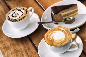 Two cups of Cappuccino coffee and chocolate mousse cake