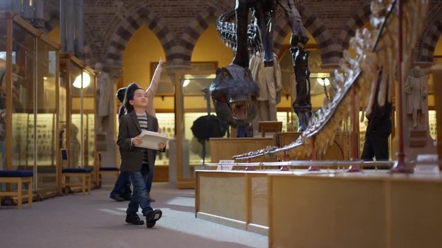  Cute little boy in museum poses to take selfie next to dinosaur exhibit