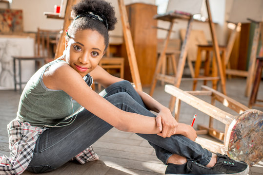 Portrait of a young african ethnicity student sitting on the floor at the studio for painting