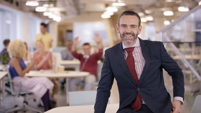  Portrait smiling business manager in office with staff clapping in background
