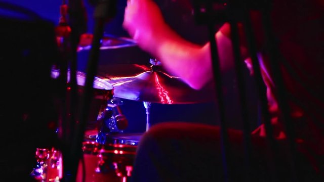 Drummer on stage. Drummer playing on drum set at a rock concert. Contrasting red and blue lights and spotlights.