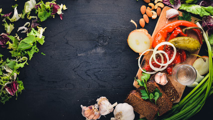 Black bread and red chili peppers with herbs and onions. Wooden on the black board.