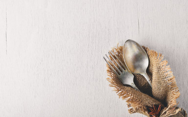 Cutlery, spoon and fork in old fabric on Wooden background. Top view. Free space.