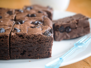 Brownies chocolate cake with plastic fork on white dish