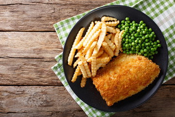 Traditional British food: Fish and chips with green peas close-up on a plate. Horizontal top view