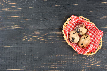 Fresh quail eggs in a basket on a dark wooden background