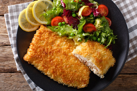 Fried fish fillet in breading and fresh vegetable salad close-up. horizontal top view