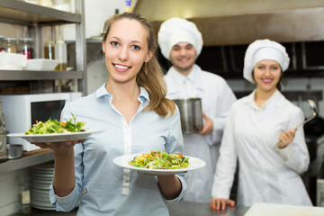 Chefs and waitress at kitchen