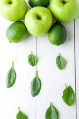 Green fruits on white wooden background. Apple, lime, spinach. Detox. Healthy food. Top view. Copy space.