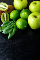 Fototapeta na wymiar Ingredients for smoothie. Green fruits on black wooden background. Apple, lime, spinach, kiwi. Detox. Healthy food. Top view. Copy space.