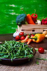 Arugula leaves in bowl. Fresh salad. Natural raw vegetables. Organic bio food on rustic wooden table.
