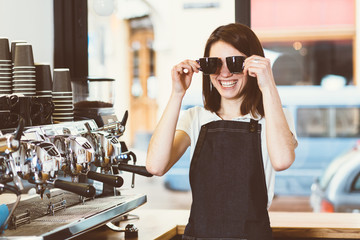 Female barista holding two small cup for espresso near face and smile