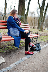 Young girl smoking cigarette outdoors sitting on bench. Concept of nicotine addiction by teenagers.