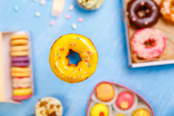 Orange glazed donut, cupcakes and macaroons. Sweet dessert. Cakes with buttercream. Almond macaron cookies. Delivery box.