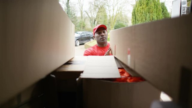 Delivery driver unloading boxes from back of van, as seen from inside vehicle