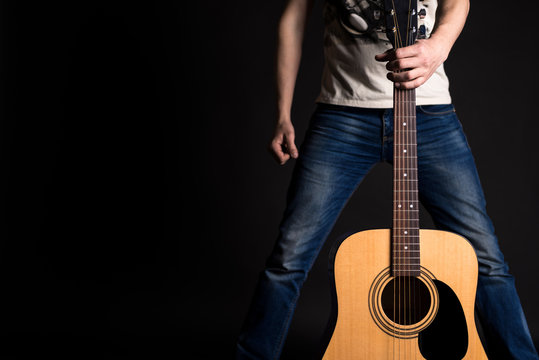 The guitarist holds his left hand with an acoustic guitar in front of him, on a black isolated background