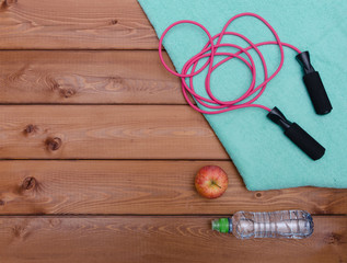 Bottle with towel water and skipping rope on wooden table