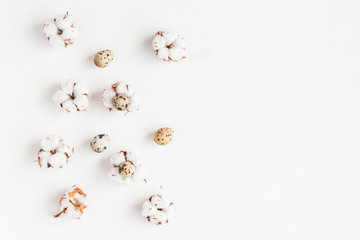 Easter quail eggs and cotton flowers on white background. Easter concept. Flat lay, top view