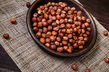 Hazelnut in bowl. Peeled nuts. Organic food on rustic wooden table with sackcloth. Top view.