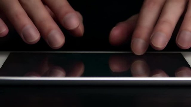 Man types text message on electronic tablet. Hands close-up.