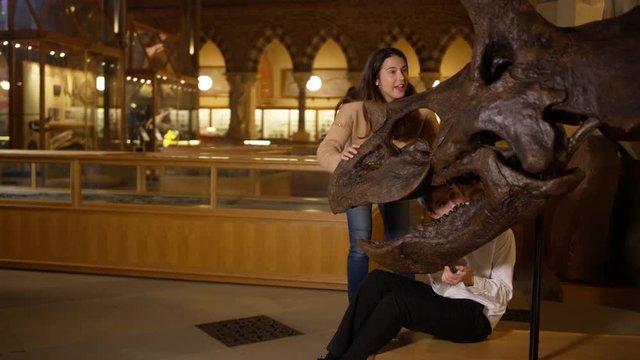  Mother & son in natural history museum looking at the skeleton of a dinosaur.