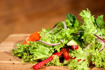 Fresh green salad on a wooden salad.