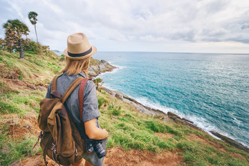 Travel concept. Young woman with camera and rucksack enjoying the sea view.