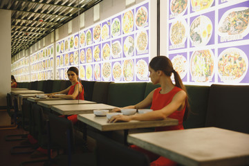 Side view woman sitting by table and looking at mirror