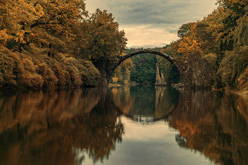Autumn, cloudy evening over Devil's bridge in the park Kromlau, Germany.Stylized photo on old, retro, vintage