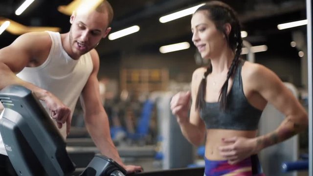 Personal trainer guiding on treadmill 