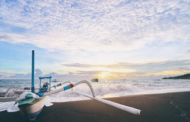 Beautiful sunrise. Ocean, beach and indonesian fishing boats.