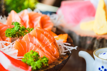 Close-up salmon raw sashimi on brown Japanese traditional dish on black table. - obrazy, fototapety, plakaty