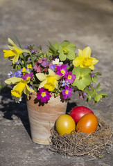 easter decoration with eggs in nest and bouquet of spring flowers