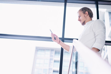 Fototapeta premium Business and technology. Handsome young man using smartphone in office.