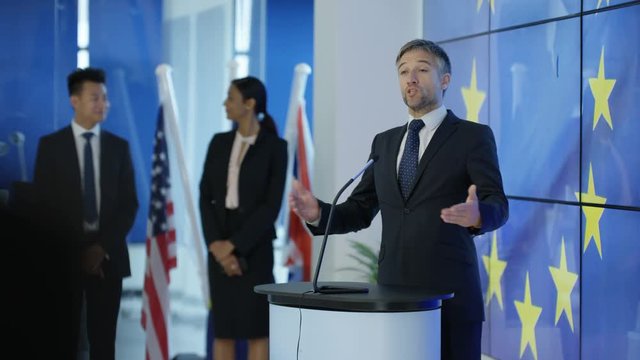  Politician making a speech at press conference, EU flag in background