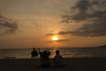 Silhouette of a couple watching a colorful sunset on a beach