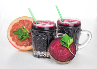 Two glass mugs with juice and beet on white wood Desk.
