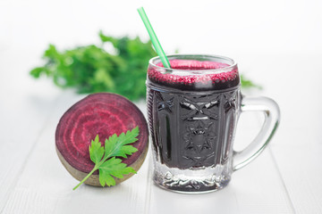 Half of the beets and beet juice in a glass mug on a white wooden table.