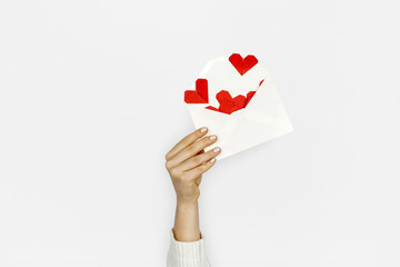 Hand holding envelope red paper hearts