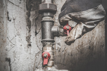 Man's hand working at pipe. Plumbing. Vintage style. Dirty job.