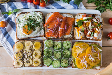 Set of toasted bread with tomato, eggs, banana, cucumber, cream cheese and salmon