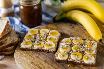 Homemade toasts with banana on wooden cutting board