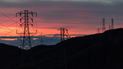 Sunset over Ocean Mountains Shape of Silhouette High Voltage Electric Power Lines Towers
