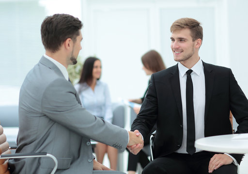 Confident business partners shaking hands and smiling
