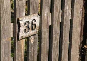 Eine verwitterte Hausnummer an einem alten Holzzaun