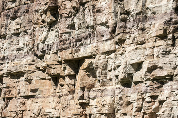 Vertical reddish wall of abandoned stone quarry closeup as natural background