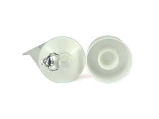 Newly open tube with a lid beside it lie on a white surface