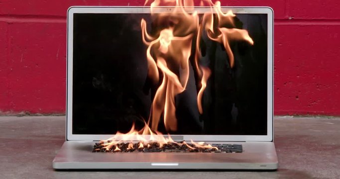 Laptop computer screen and keyboard on fire in slow motion