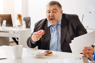 Hilarious chubby employee having a lunch during a busy week